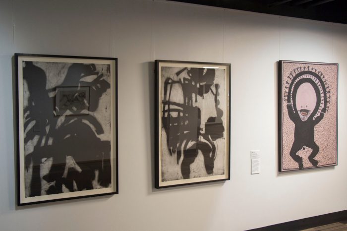 Photo of a gallery wall featuring three large framed paintings.