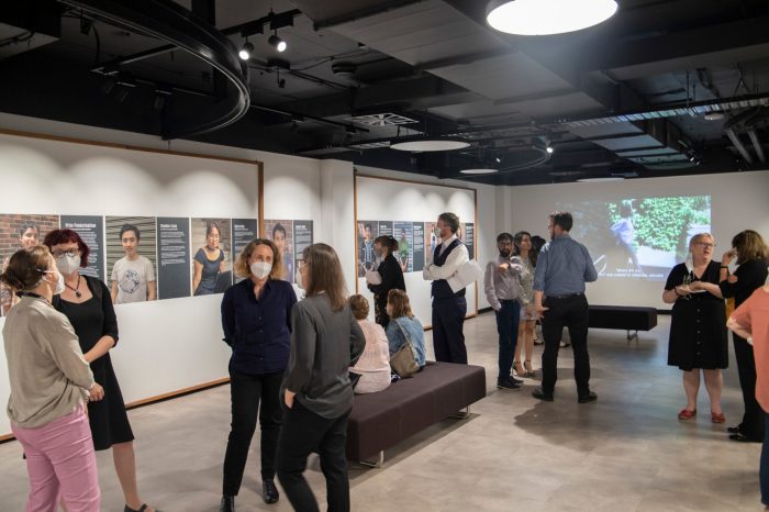 A room filled guests stand speaking and looking at the portraits on show.