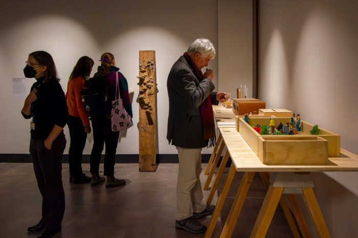 Guests mingle in the exhibition space while a man wearing a jacket smells a vial of essential oils