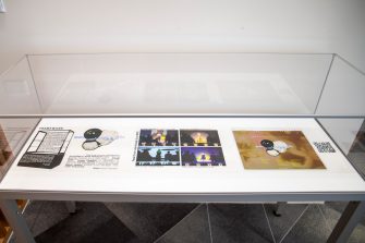 A front on view of a glass display unit containing three transparent sheets printed with text and abstract images 