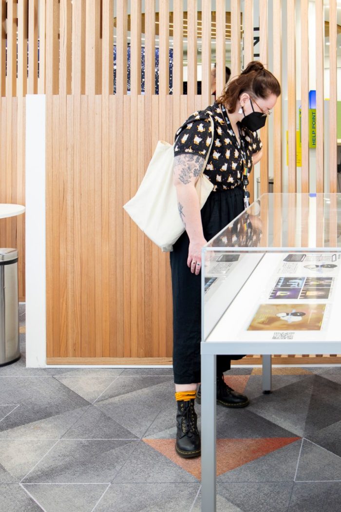 Photo of a person looking a display cabinet containing colourful posters