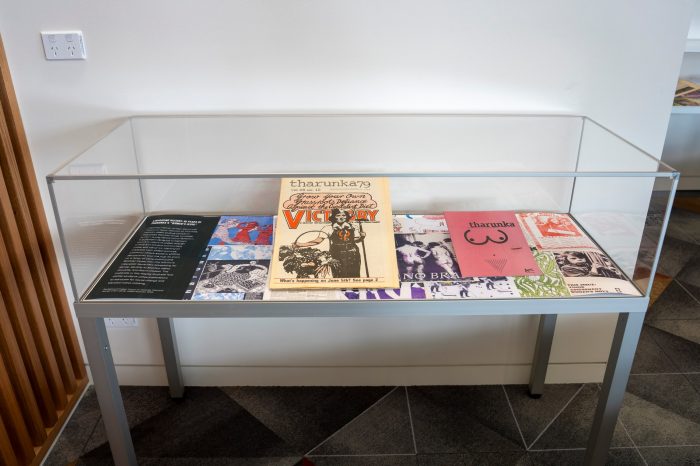 A glass display cabinet containing two magazines propped up against a colourful backdrop