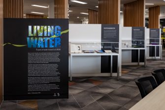 A view of three display cases against a series of zig-zagged walls. The first wall is black with the text "Living Water" written in sea-blue.